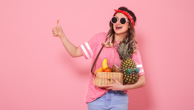 Portrait d'une jeune fille avec des aliments sains, des fruits, sur un mur rose