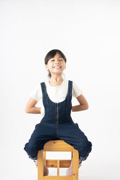 Portrait de jeune fille asiatique cacher quelque chose à l'arrière, isolé sur fond blanc