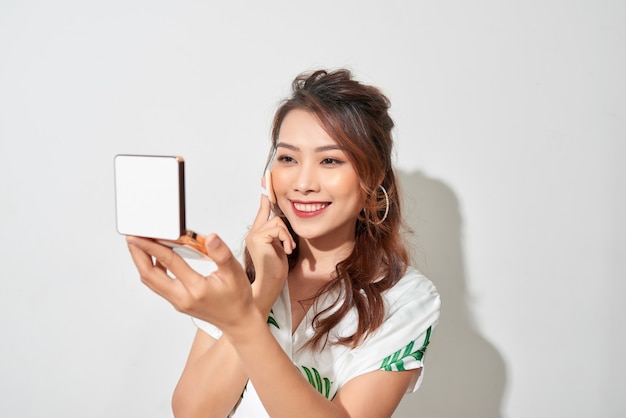 Portrait de jeune fille asiatique dans le style vestimentaire d'été, faire du maquillage avec son petit miroir et de la poudre