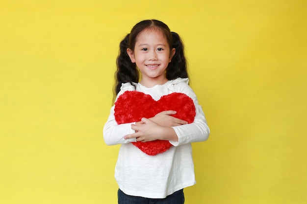 Portrait de jeune fille asiatique souriante tenant un coeur rouge