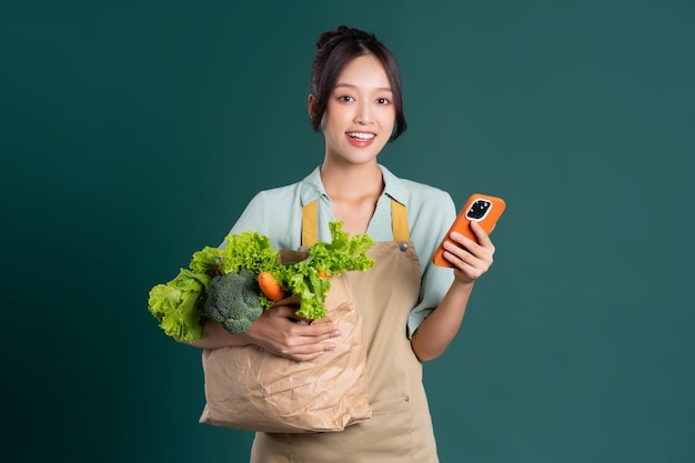 Portrait de jeune fille asiatique tenant un sac de légumes sur fond vert