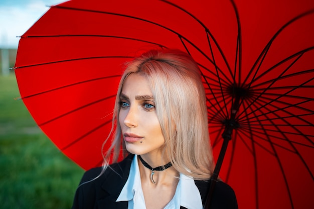 Portrait de jeune fille assez blonde sur fond de parapluie rouge.