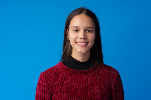 Portrait de jeune fille assez souriante sur fond bleu en studio