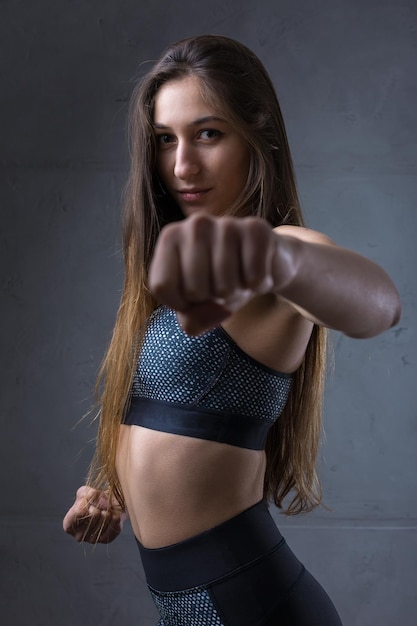 Portrait d'une jeune fille athlétique mince contre un mur de béton dans un intérieur d'appartement à la mode