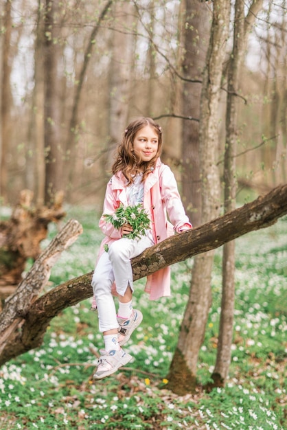 Portrait d'une jeune fille au bouquet d'anémone. Un enfant dans la forêt au printemps.