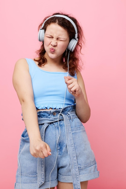 Portrait d'une jeune fille au casque écoutant de la musique sur un fond rose inchangé