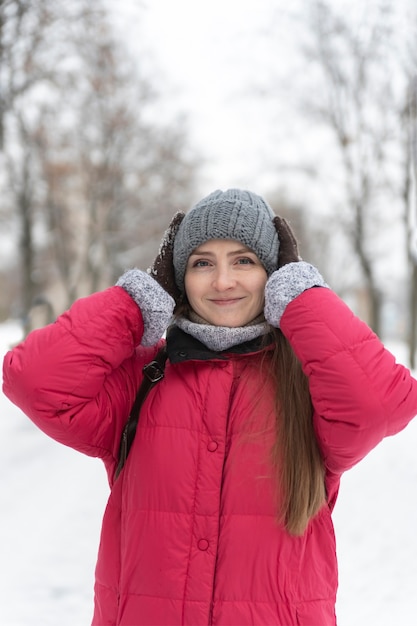 Portrait de jeune fille au chapeau chaud sur fond de parc d'hiver. Cadre vertical.