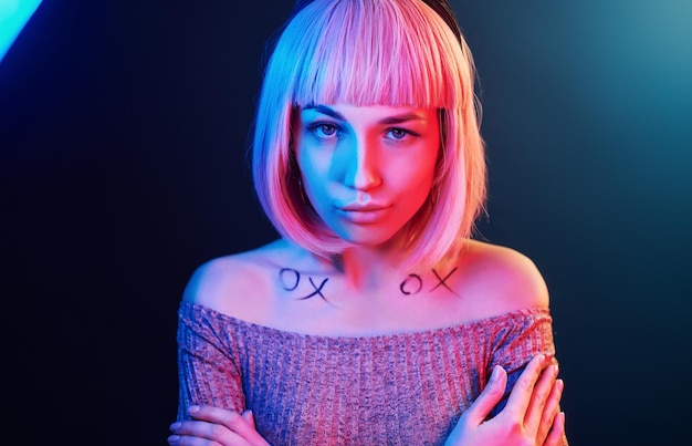 Portrait de jeune fille aux cheveux blonds en néon rouge et bleu en studio