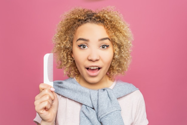 Portrait d'une jeune fille aux cheveux bouclés. Elle tient une petite brosse blanche dans ses mains