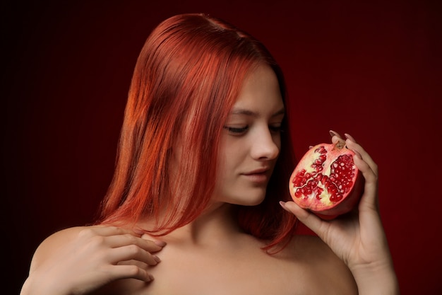 Portrait d'une jeune fille aux cheveux rouges et fruits de grenade dans les mains