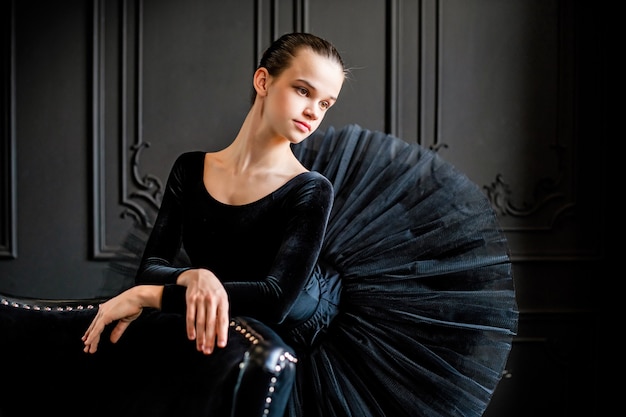 Portrait d'une jeune fille de ballerine dans un tutu noir sur un espace sombre