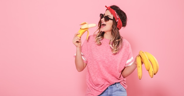 Portrait d'une jeune fille et des bananes isolés sur mur rose