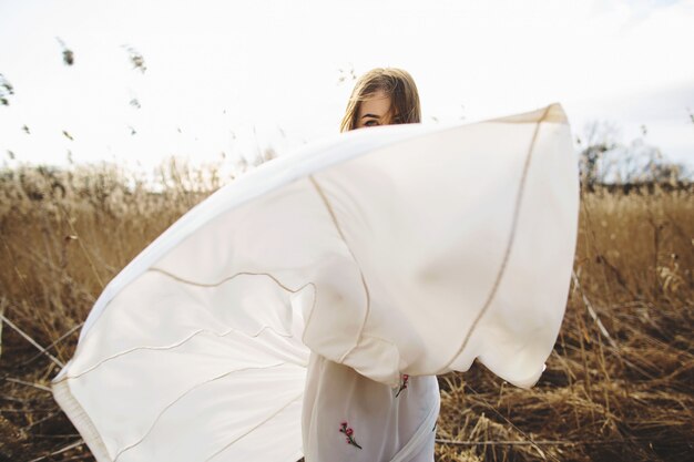 Portrait de jeune fille belle à la robe blanche dans le champ de blé, à pied, sans soucis.