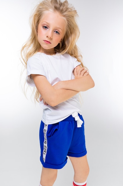 Portrait de jeune fille blonde charmante et séduisante en tenue de sport est debout sur un fond blanc.