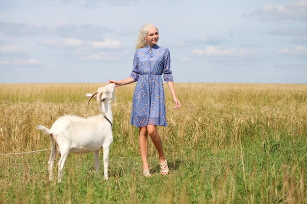 Portrait d'une jeune fille blonde avec une chèvre dans un champ de blé