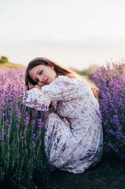 Portrait d'une jeune fille blonde dans un champ de lavande en été au coucher du soleil