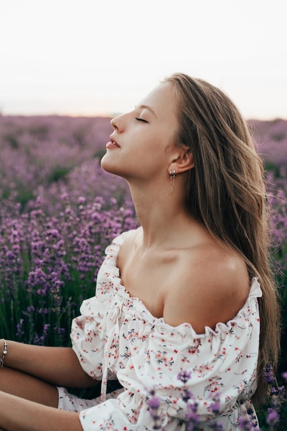 Portrait d'une jeune fille blonde dans un champ de lavande en été au coucher du soleil