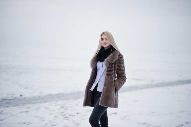 Portrait de jeune fille blonde élégance dans un fond de manteau de fourrure rivière brumeuse sur la glace d'hiver