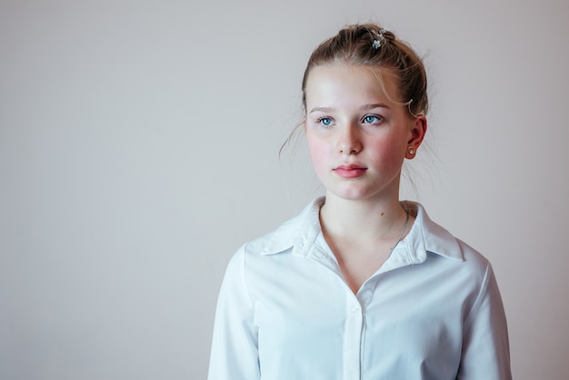 Portrait de jeune fille blonde avec ses cheveux mis dans un chignon portant une chemise blanche