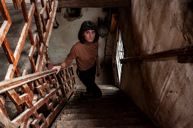 Portrait D'une Jeune Fille Brune Dans Un Escalier D'une Maison Abandonnée, Image En Basse Lumière