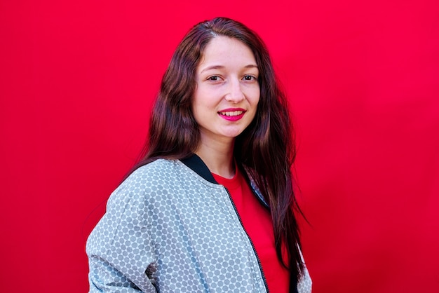 Portrait d'une jeune fille brune avec du rouge à lèvres rouge sur fond plat rouge