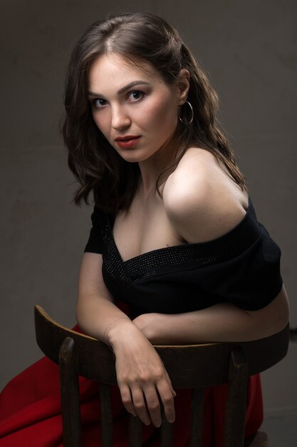 Portrait d'une jeune fille brune sexy dans un haut en dentelle dans des tons dramatiques. Photo d'époque.