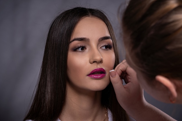 Portrait de jeune fille brune en studio, préparation correcte du maquillage