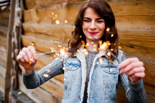 Portrait de jeune fille brune en veste jeans avec feux de Bengale dans les mains.