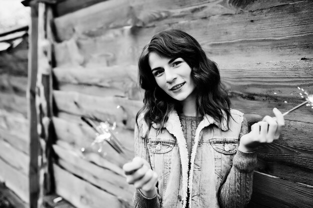 Portrait de jeune fille brune en veste jeans avec feux de Bengale dans les mains.