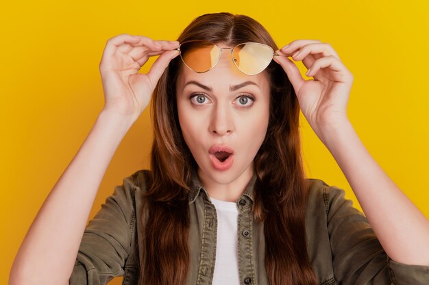 Portrait de jeune fille choquée regarde avec la bouche ouverte isolée sur fond jaune