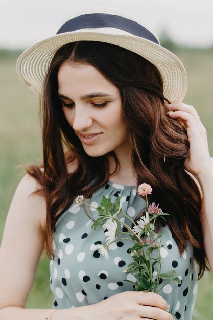 Portrait d'une jeune fille dans un chapeau de paille dans un champ vert d'été