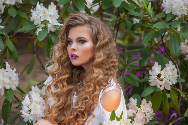 Portrait d'une jeune fille dans des jardins fleuris rhododendron blanc Cheveux longs et beau maquillage