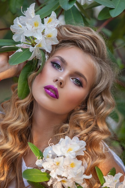 Photo portrait d'une jeune fille dans des jardins fleuris rhododendron blanc cheveux longs et beau maquillage