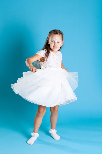 Portrait d'une jeune fille dans une robe de princesse blanche avec une jupe tourbillonnante et dansant