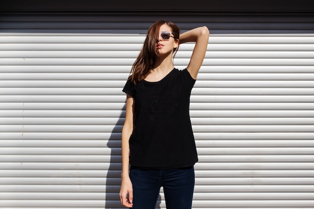 Portrait de jeune fille dans un style rock noir debout à l'extérieur de la ville contre le mur urbain en métal argenté