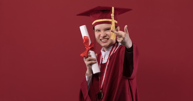 portrait d'une jeune fille diplômée dans un bonnet de graduation sur fond rouge