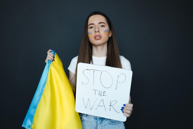 Portrait de jeune fille avec le drapeau ukrainien bleu et jaune sur sa joue sur le fond noir