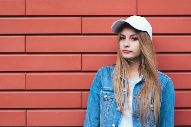 Portrait de jeune fille élégante sur fond de briques