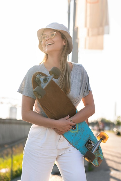 Portrait de jeune fille élégante portant un chapeau de Panama avec un longboard dans une ville