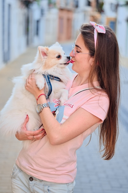 Portrait d'une jeune fille embrassant son chien poméranien blanc moelleux.