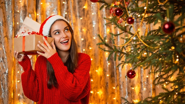 Portrait de jeune fille heureuse émotionnelle essayant de deviner quel cadeau elle a