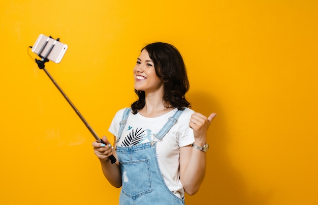 Photo portrait d'une jeune fille heureuse faisant selfie isolé sur mur jaune