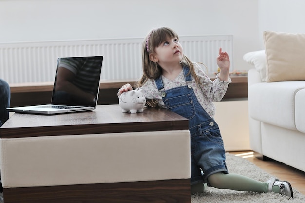 portrait de jeune fille heureuse à la maison tout en peignant la tirelire et représentant le concept bancaire et financier