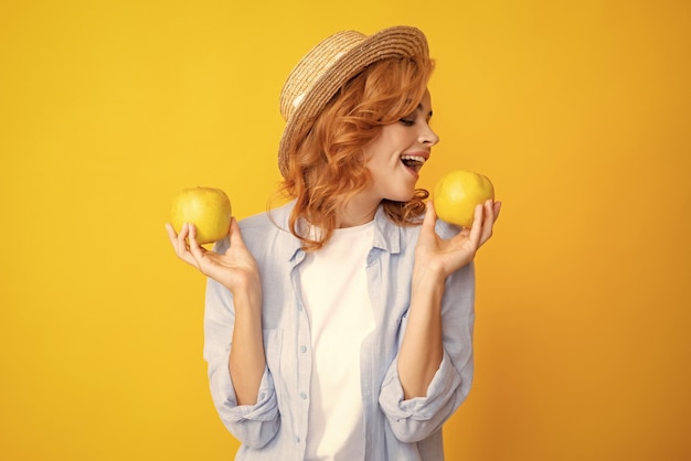 Portrait d'une jeune fille heureuse tenant une pomme verte isolée sur fond jaune Une femme caucasienne heureuse tient une pomme verte fraîche et sourit