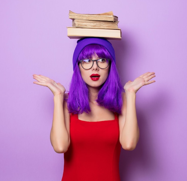 Photo portrait de jeune fille hipster de style aux cheveux violets et livres sur fond de couleur violette