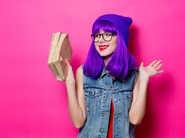 Portrait de jeune fille hipster de style aux cheveux violets et livres sur fond rose