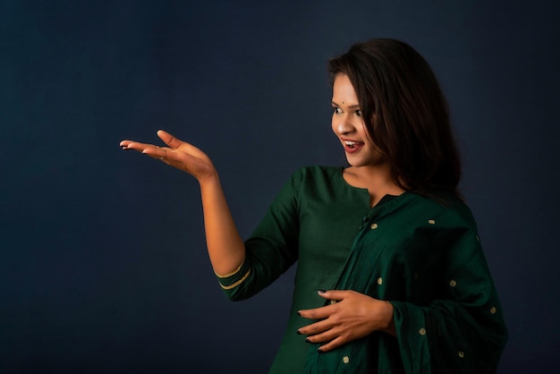 Portrait d'une jeune fille joyeuse réussie tenant et présentant quelque chose à portée de main avec un visage souriant heureux