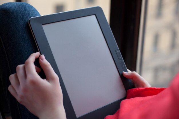 Portrait d&#39;une jeune fille lisant un livre électronique.