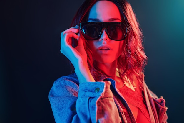 Portrait de jeune fille à lunettes de soleil en néon rouge et bleu en studio