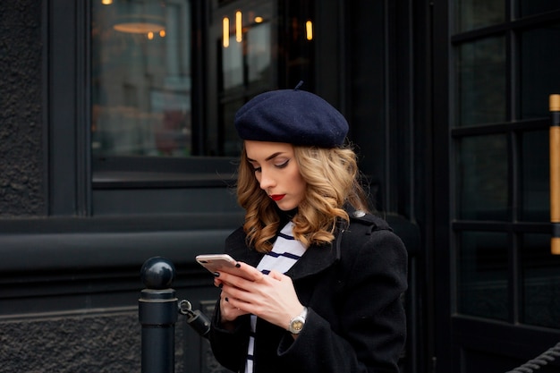 Portrait de jeune fille à la mode en regardant son téléphone